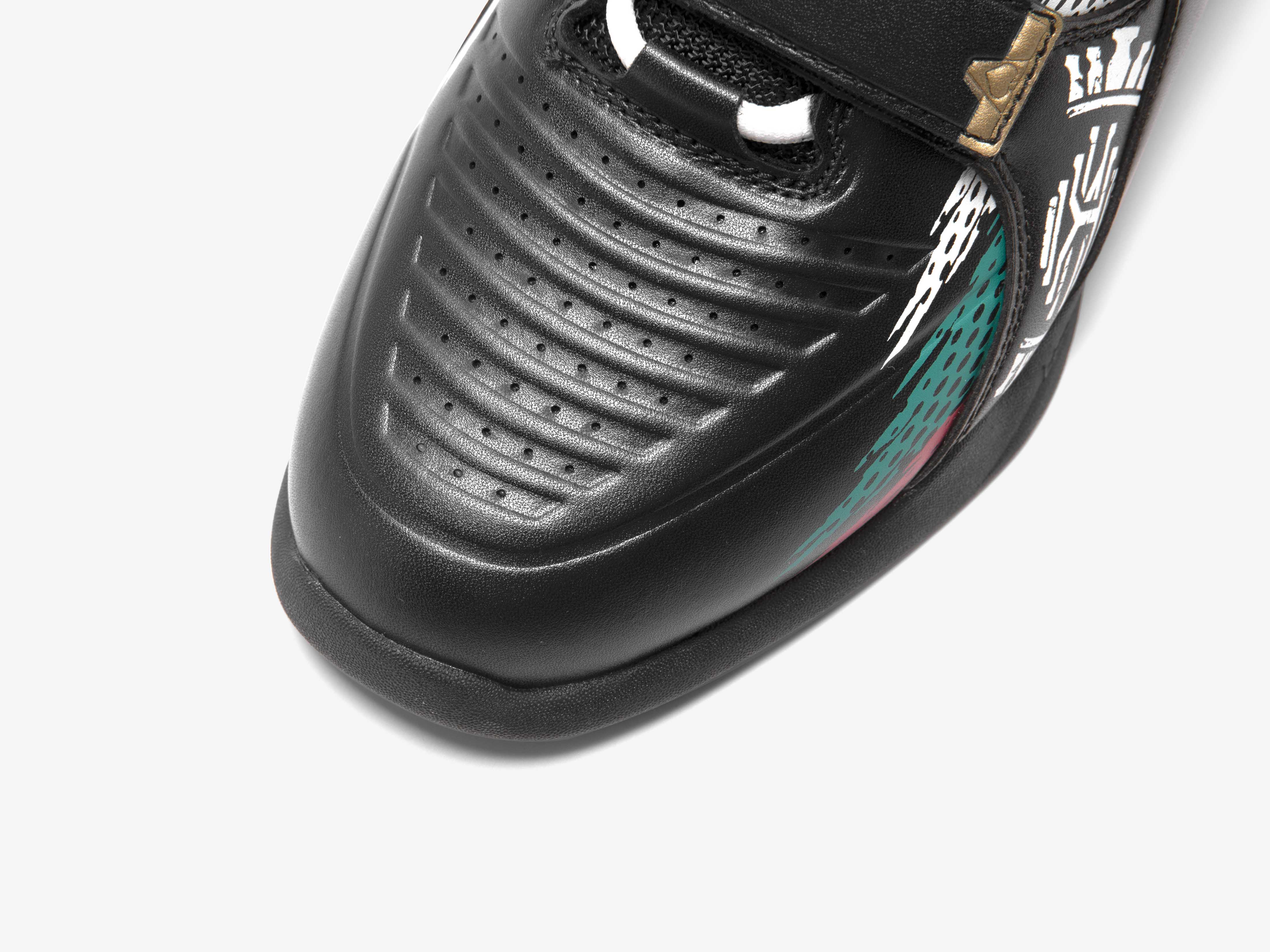 Close-up of a black and red Karlos Edition toe box with a brand logo on a white background