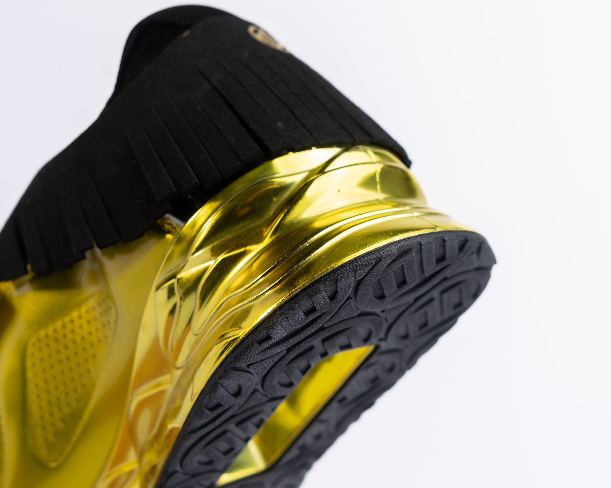 Close-up of a black and yellow gold weightlifting shoes on a light gray background