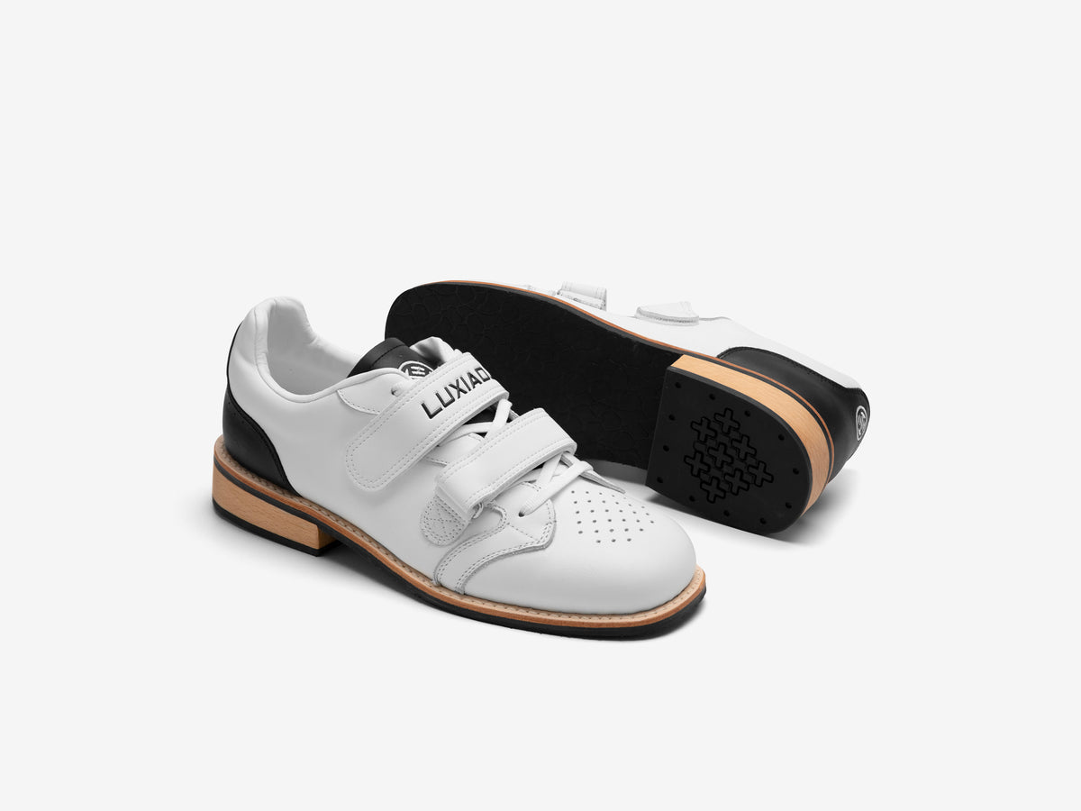 Pair of white LUXIAOJUN Heritage Lifter weightlifting shoes, one turned over to show the black outsole